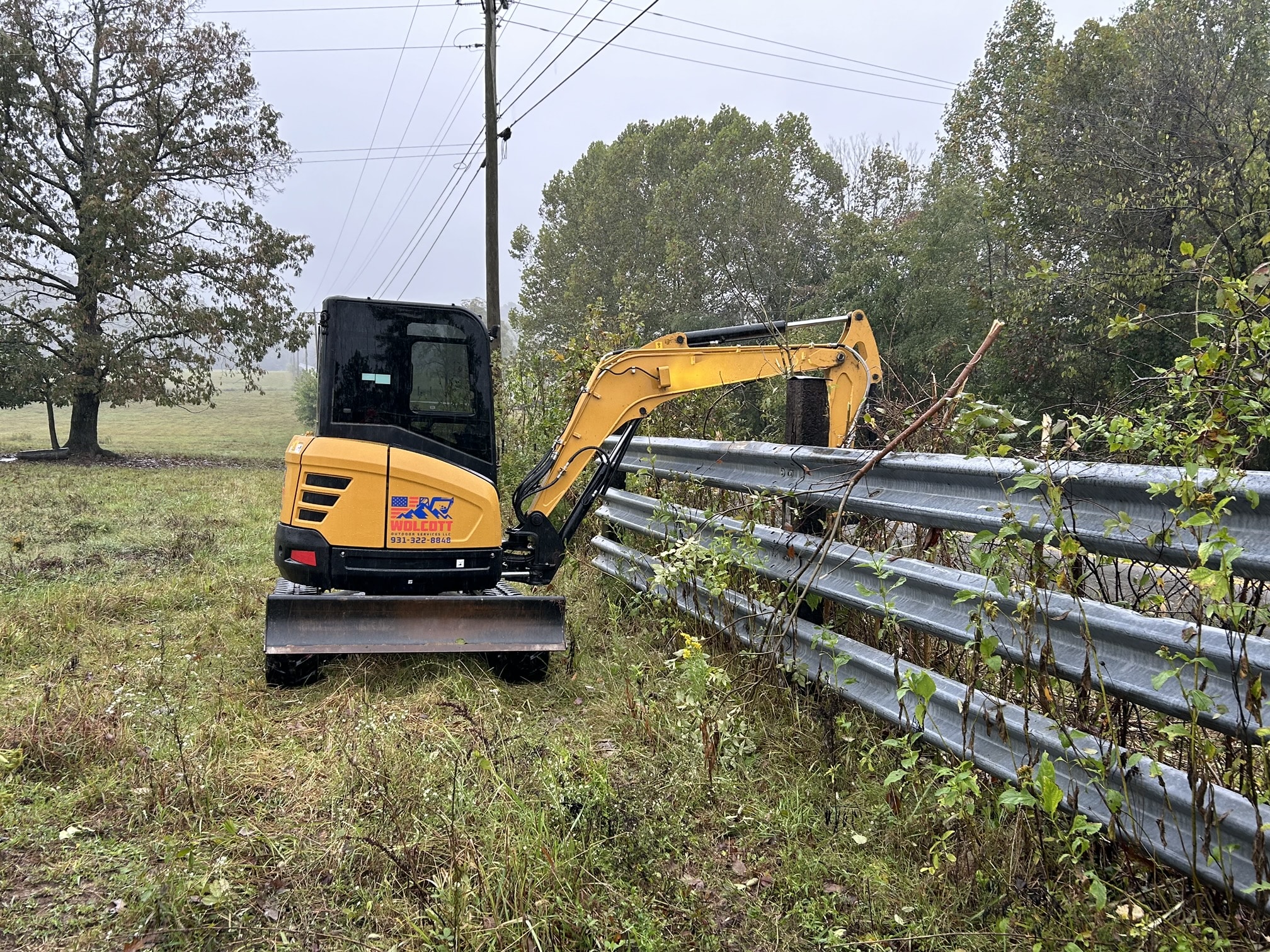 Excavator operating next to a metal guardrail